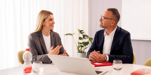 Kandidatin mit Kaufland-Mitarbeiter in einem Konferenzraum der Zentrale beim Bewerbungsgespräch. Auf dem Tisch steht ein aufgeklappter Laptop.
